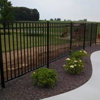 A black metal fence surrounds a lush green field.