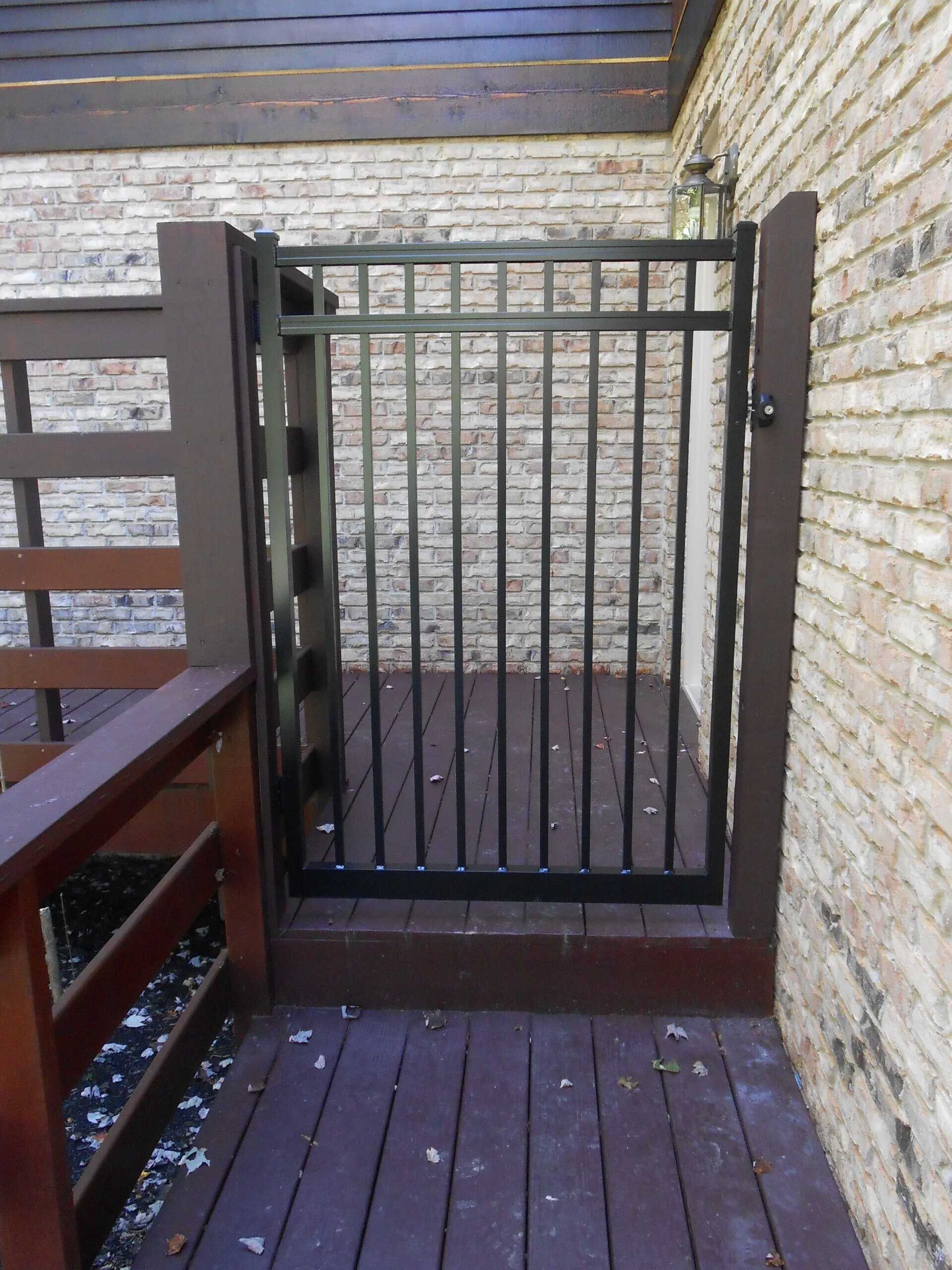 A wooden deck with a metal gate in front of a brick wall
