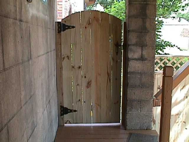 A wooden gate is open to a brick wall