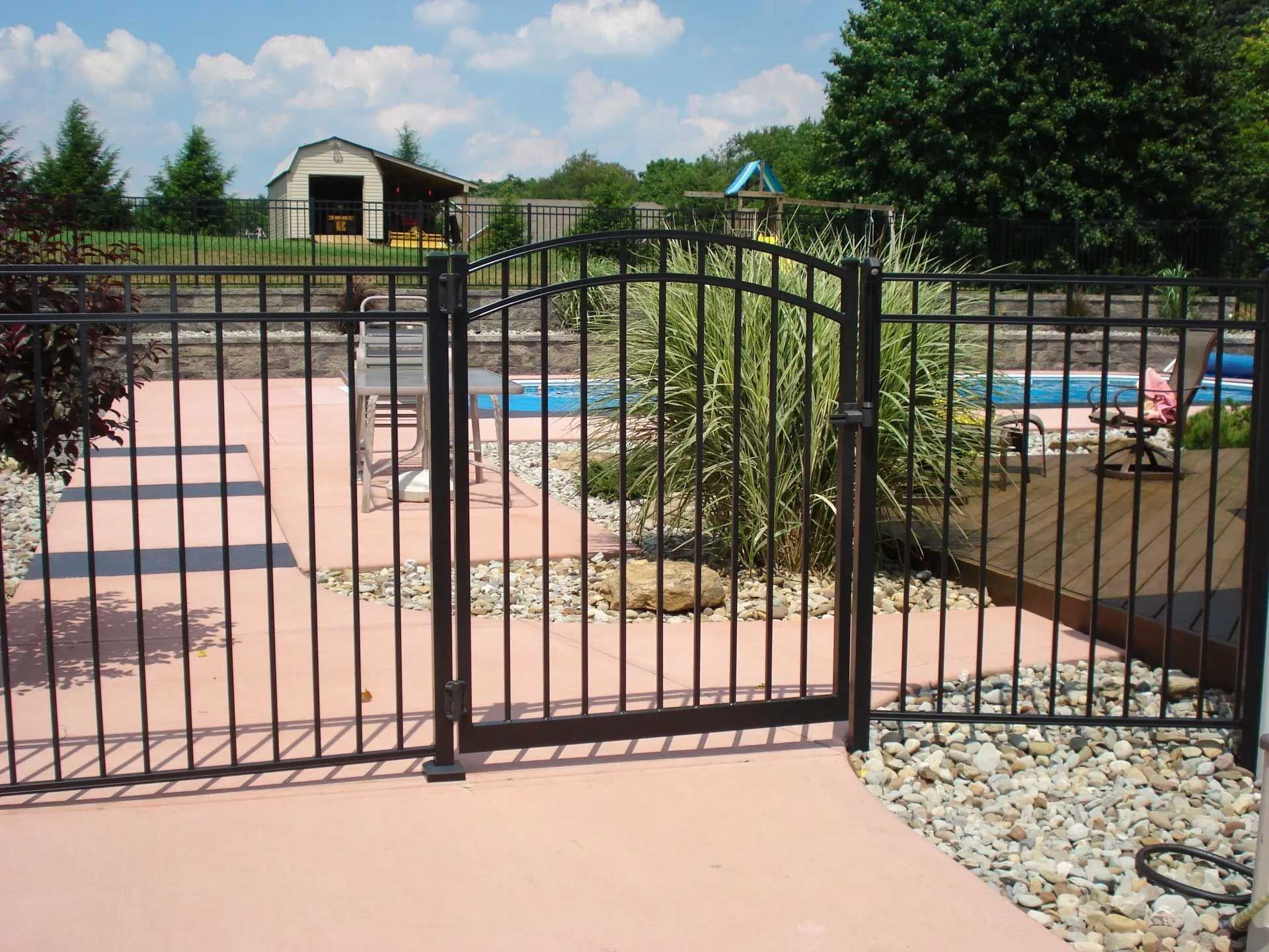 A black metal fence surrounds a swimming pool