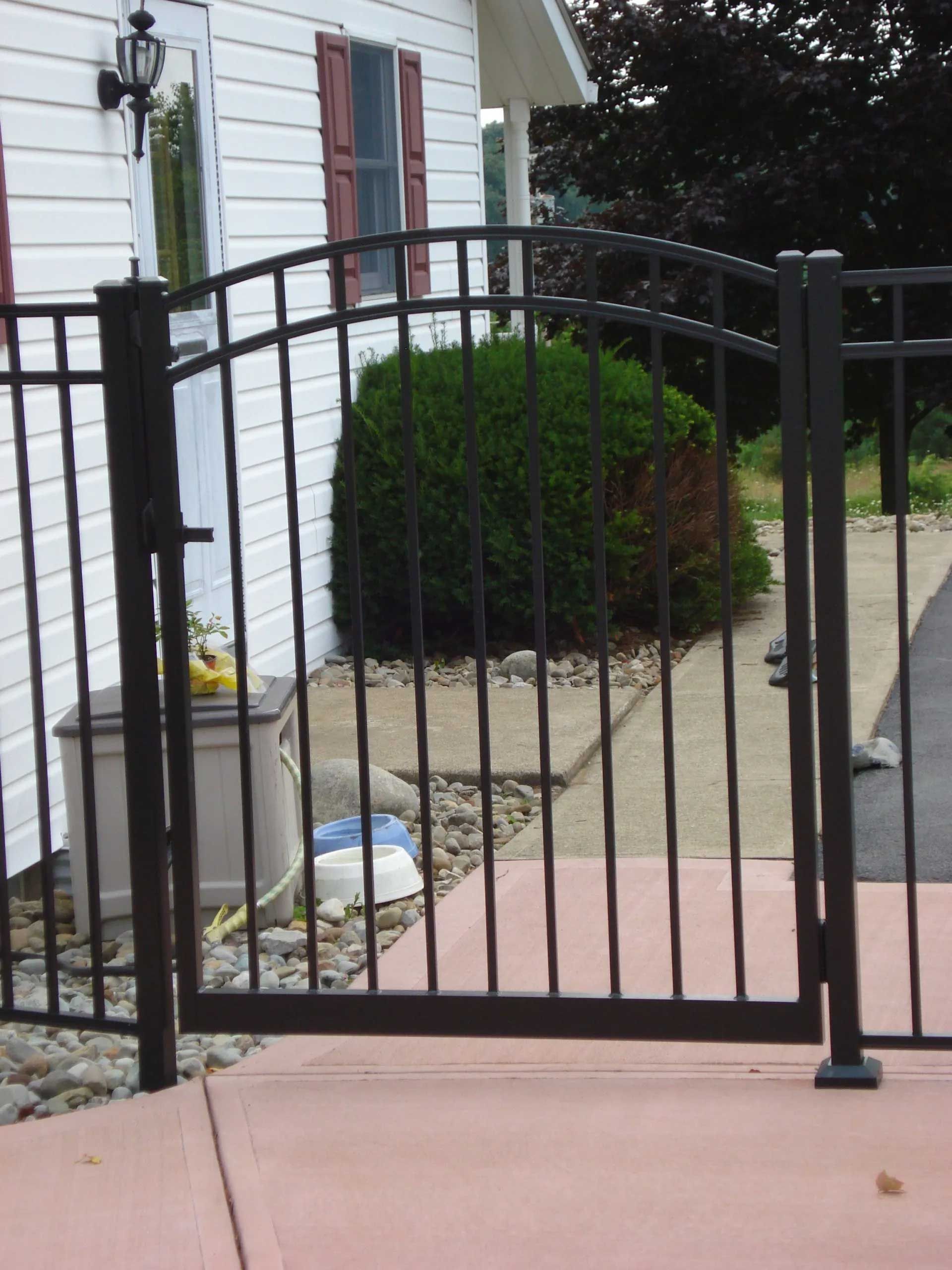 A black gate is open in front of a white house