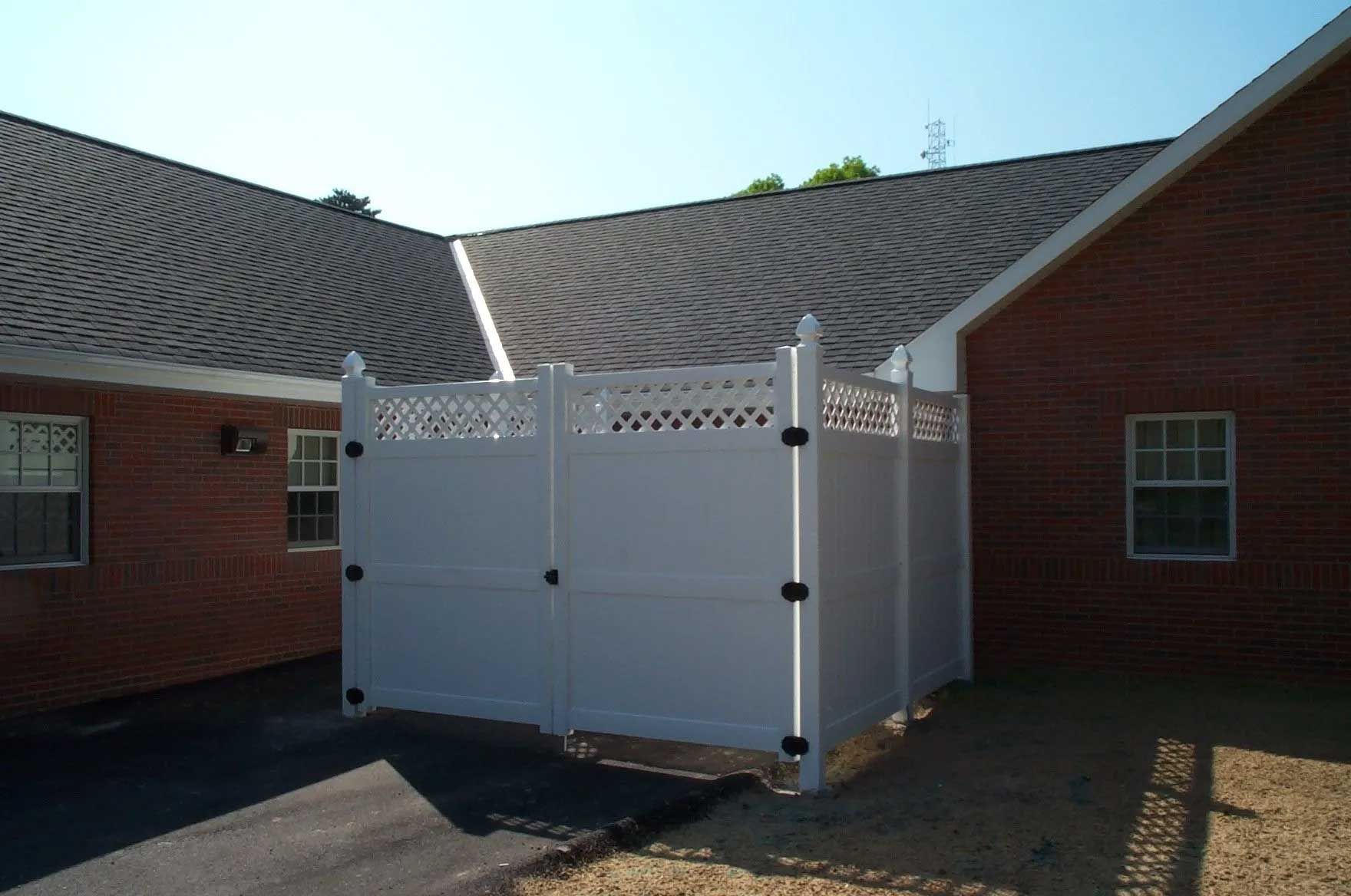 A white fence is in front of a brick building