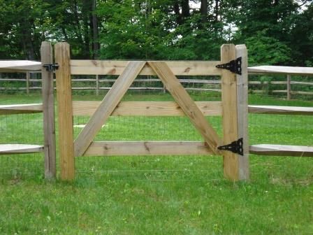 A wooden gate is in the middle of a grassy field