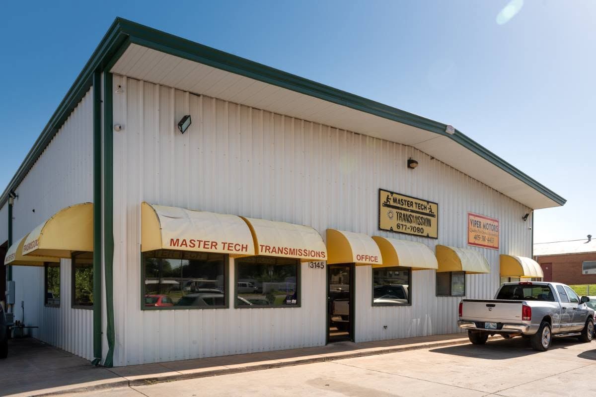 White commercial building with yellow awnings and a parked pickup truck outside under a clear sky