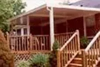 Wooden porch with screened-in area, attached to a brick building. Stairs lead up to the porch.