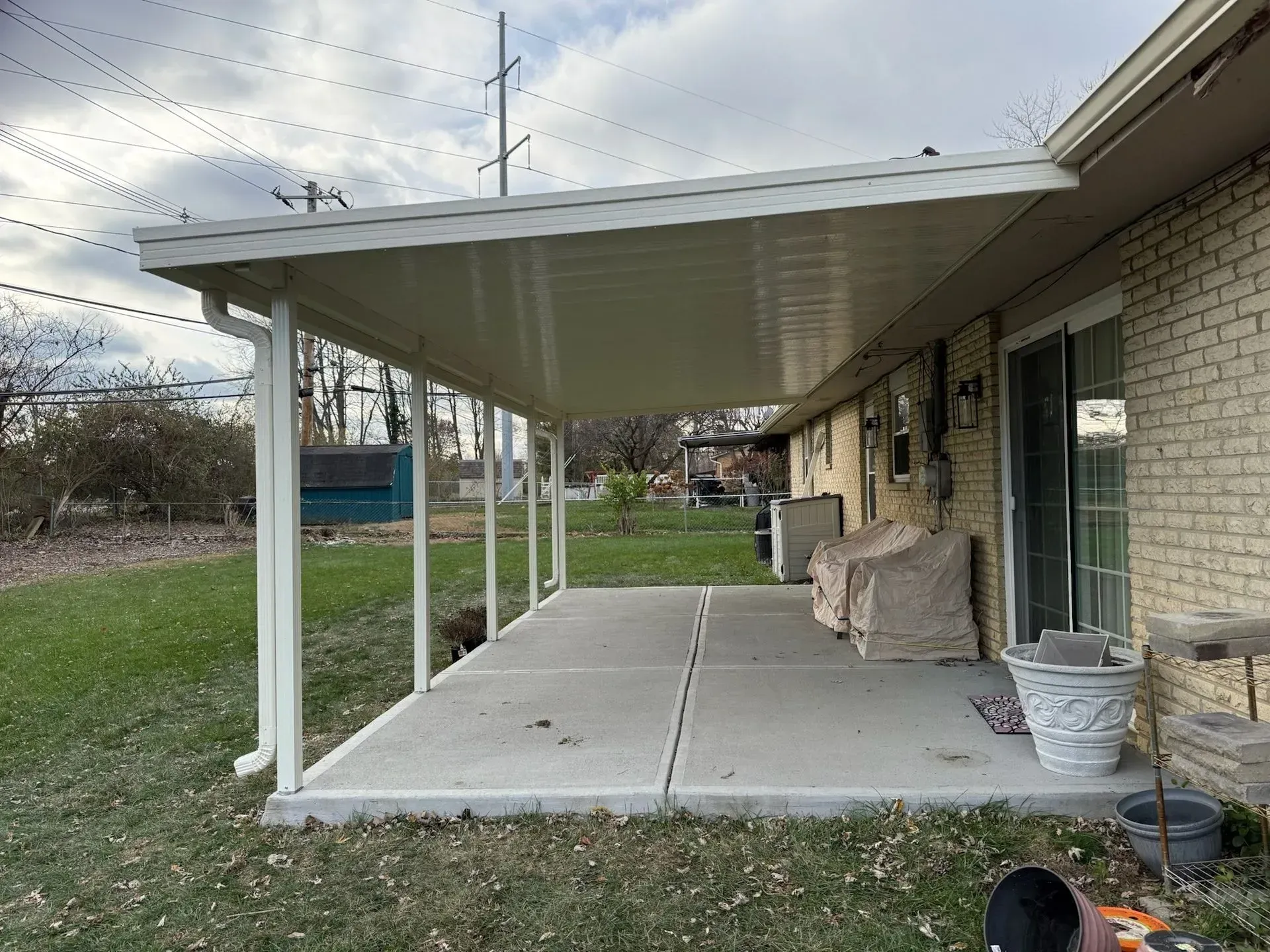 A patio with a white covered roof attached to a brick house.
