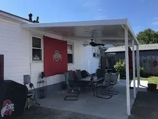 Backyard patio with an Ohio State flag, dining table, and white awning.