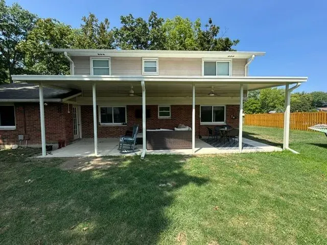 Two-story house with a covered patio in the backyard, green grass in front.