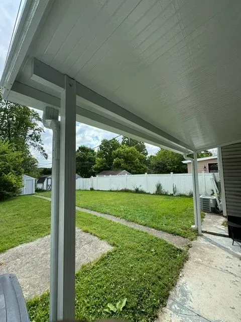 White-roofed patio with vertical support posts overlooking a grassy yard.