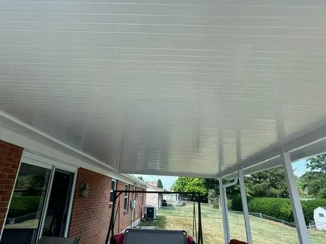 White patio ceiling with a view of a brick house, yard, and swing set.