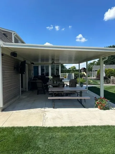 Patio with white canopy, picnic table, and outdoor seating on a sunny day.