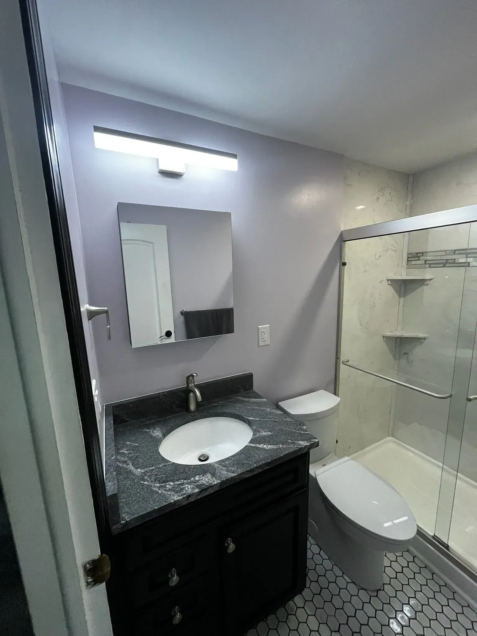 Bathroom with dark vanity, white sink, and tiled shower.