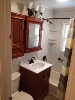 Bathroom with dark wood vanity, toilet, and medicine cabinet; white fixtures and walls.