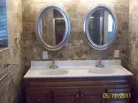 Bathroom with a double vanity. Oval mirrors hang above the sinks. Tile walls.