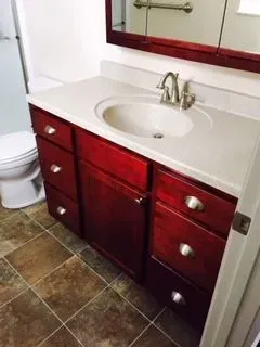 Bathroom vanity with a dark red cabinet, white countertop, and silver faucet.