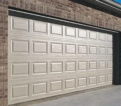Beige panel garage door on a brick building.
