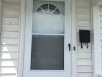 White screen door with a black mailbox on white siding.