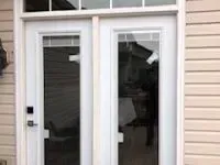 White double doors with glass panels and a transom window. Beige siding.
