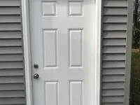 White door with six panels in a gray wall.