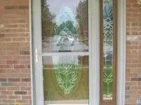 A brick building with a door and sidelight, both with decorative stained glass panels.
