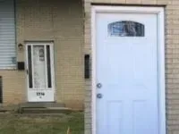 Two exterior doors, one with glass, both white, on brick building.