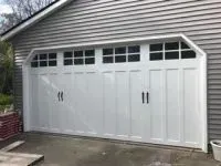 White garage door with windows, on a house with gray siding.