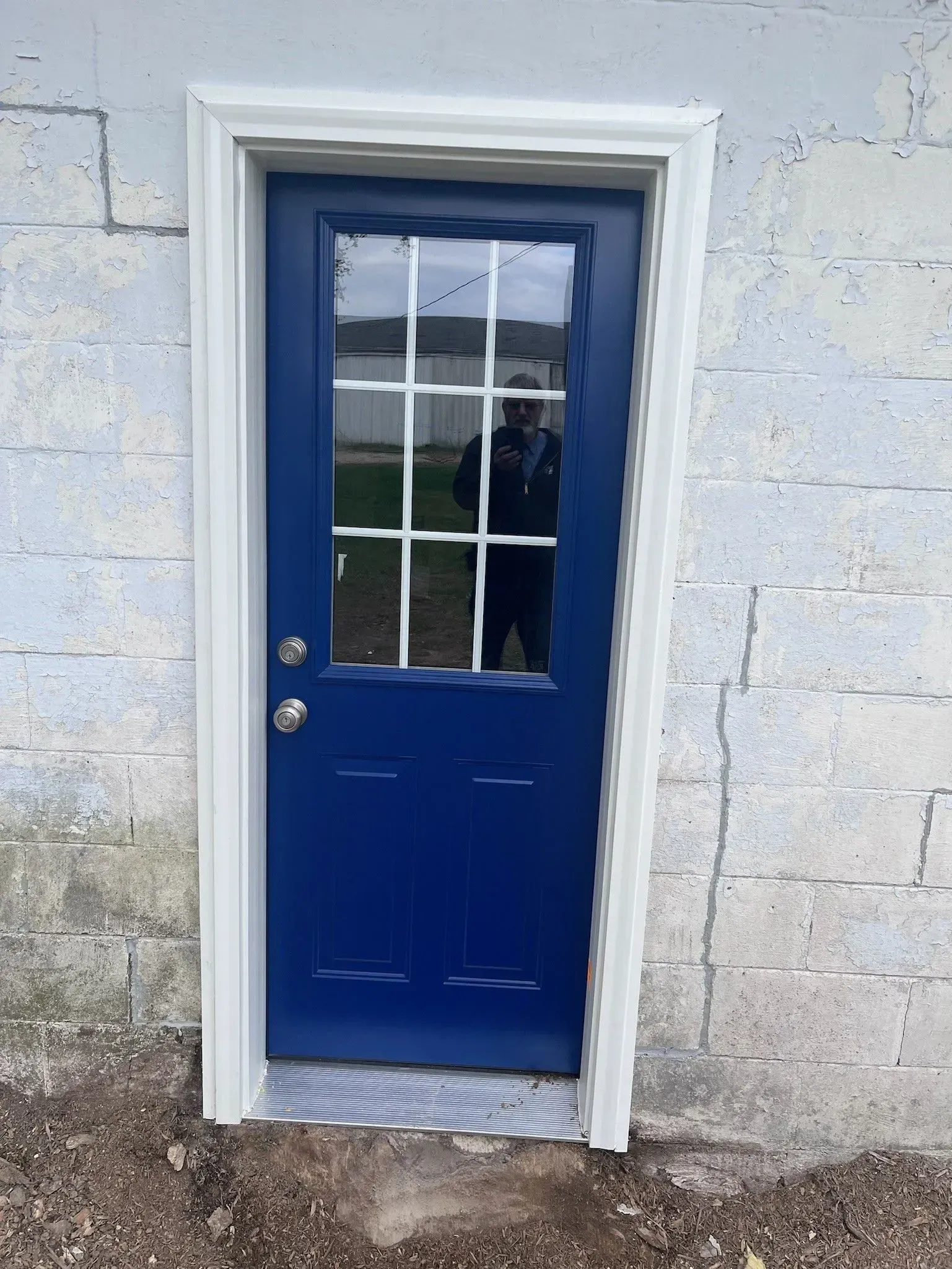 Blue exterior door with glass panes and white trim in a brick wall.