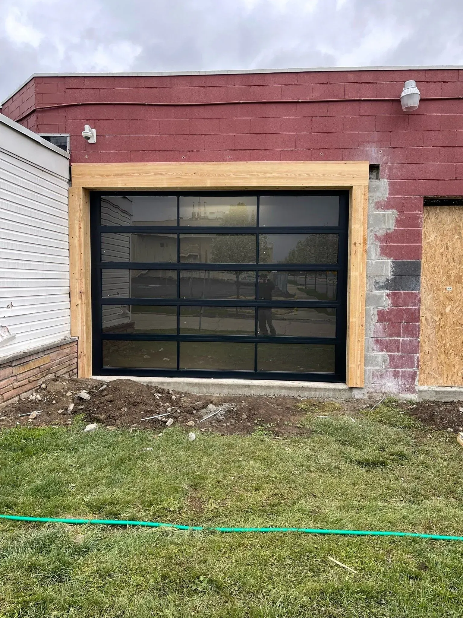 Garage door framed in light wood installed in a red brick building.