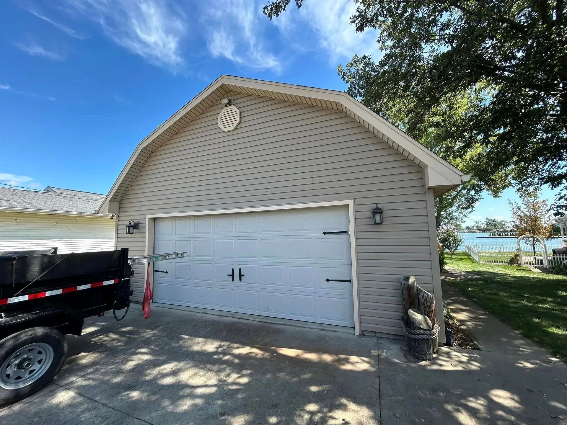 Tan garage with white garage door, black hardware, and two outdoor lights.