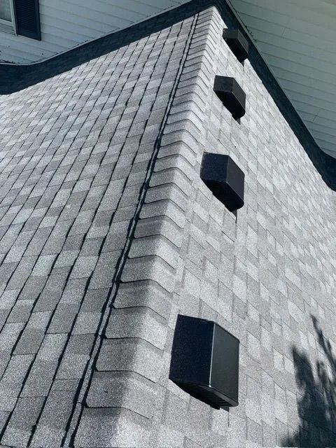 Gray shingle roof with black ventilation caps along the edge.
