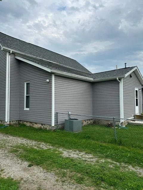 Gray house with gray siding, white trim, and a cloudy sky.