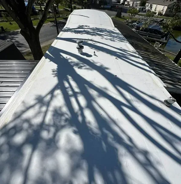 White RV roof with long tree shadows and surrounding houses.