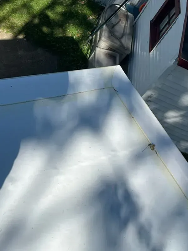 White roof corner; shadows, side of building and green grass visible.