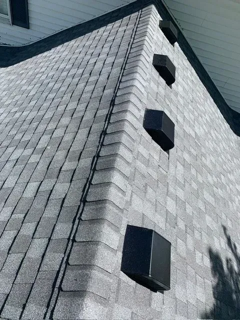 Gray shingle roof with black vent pipes along a corner. White trim on a gabled side.
