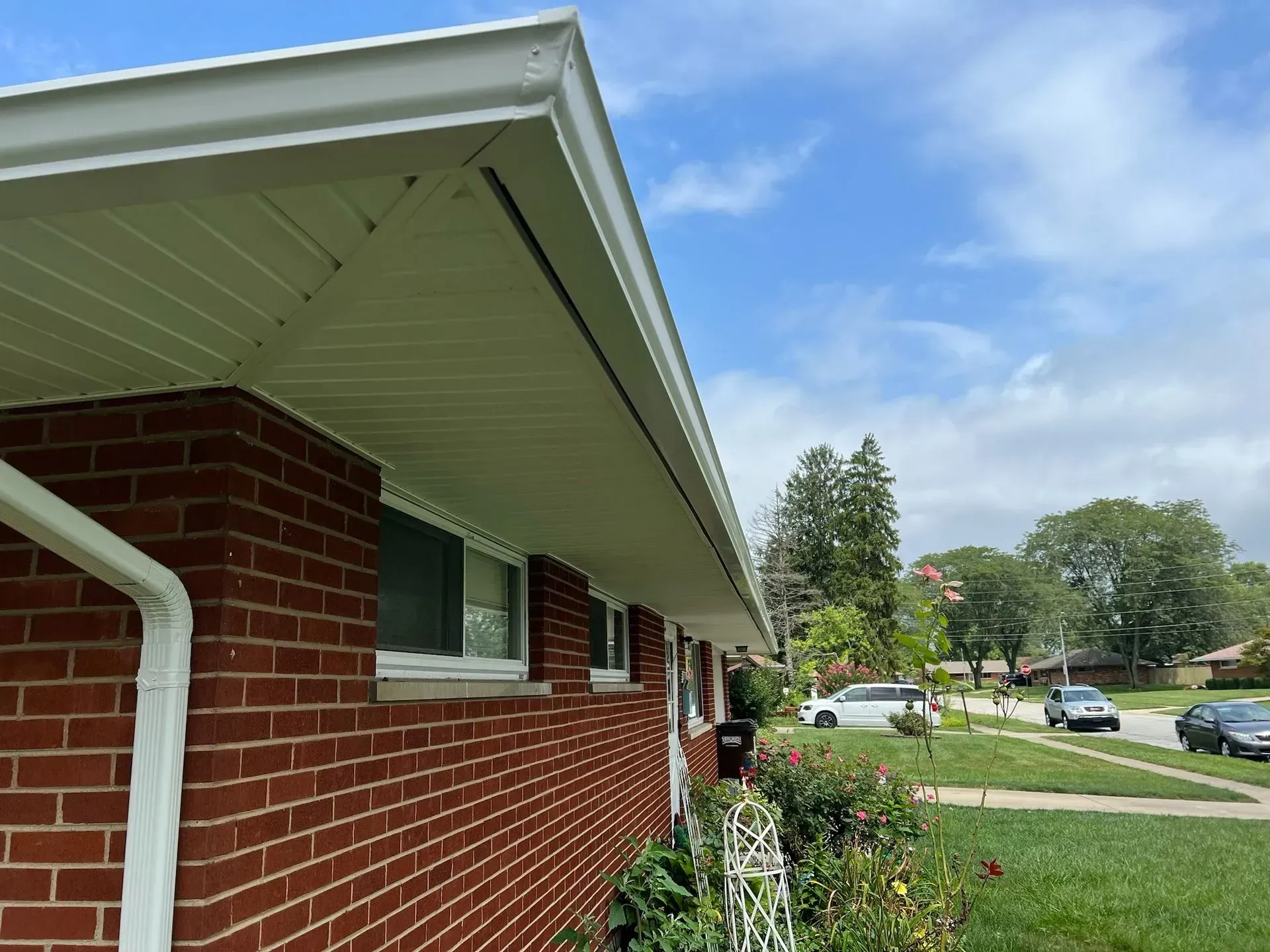 Red brick house exterior with white trim and a green lawn under a cloudy sky.