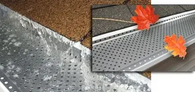 Gutter with mesh cover, water flowing over, leaves on roof.