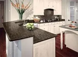 Kitchen with dark granite countertop, white cabinets, and a vase of flowers.