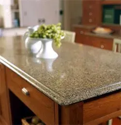 Kitchen island with granite countertop and a white vase holding green grapes.