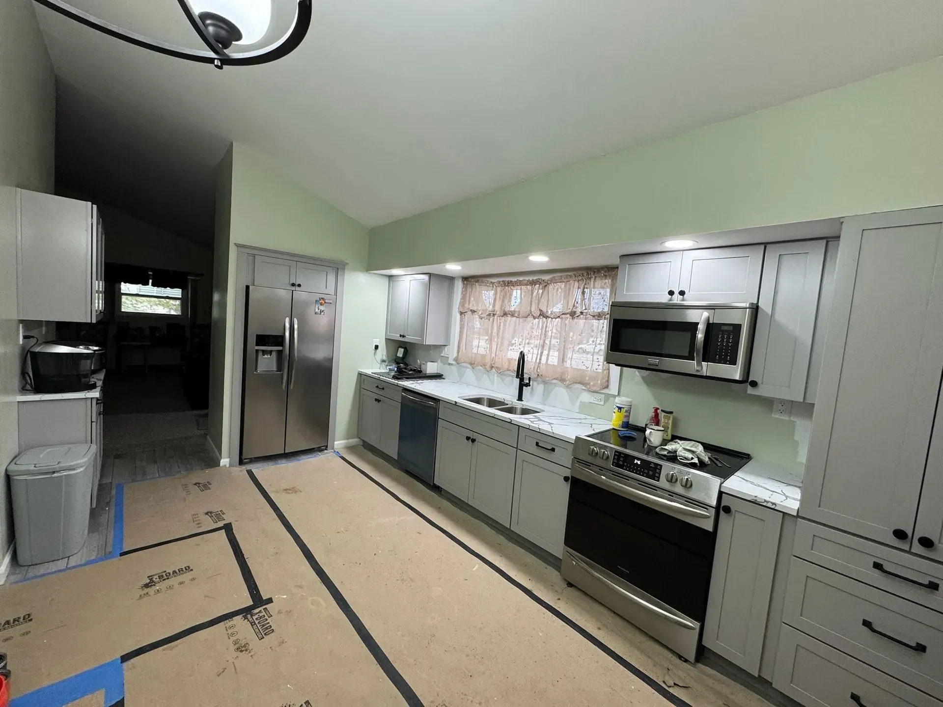 Kitchen with light gray cabinets, stainless steel appliances, and sage green walls.