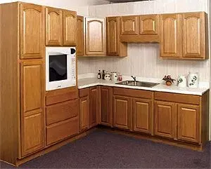 Kitchen cabinets with a built-in microwave, wood finish, white countertops, and a sink.