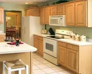 Kitchen with light wood cabinets, white appliances, and a tiled floor.
