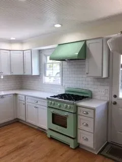 Kitchen with white cabinets, light wood floor, and mint green appliances.