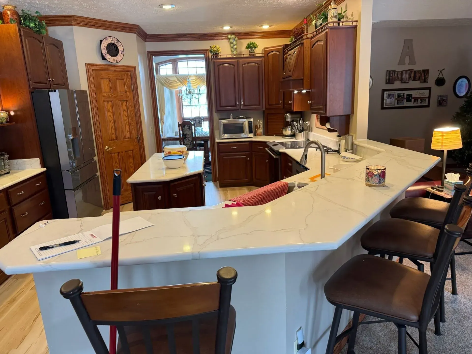 Kitchen with wooden cabinets, white countertops, and bar stools.