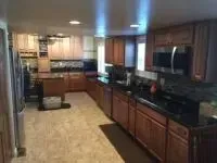 Spacious kitchen with wood cabinets, dark countertops, and tile flooring.