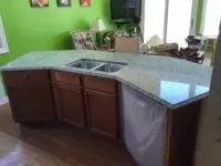 Kitchen island with granite countertop, cabinets, and a sink.