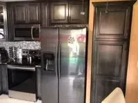 Kitchen with dark cabinetry, stainless steel appliances, and a tiled backsplash.