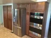 Kitchen with stainless steel refrigerator, double oven, and wood cabinets.