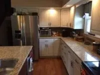 Kitchen with light cabinets, stainless steel refrigerator, granite countertops, and wood floors.