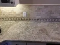 Kitchen countertop with beige backsplash tiles and decorative diamond border.