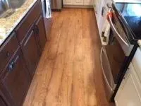 Kitchen with hardwood floors, dark cabinets, and stainless steel oven.